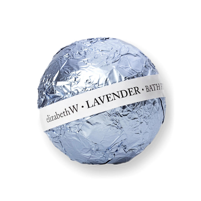 A round lavender bath fizz ball by E Wightman & Co, wrapped in shiny silver foil with a white label reading "BATH FIZZ BALL LAVENDER" around the center.