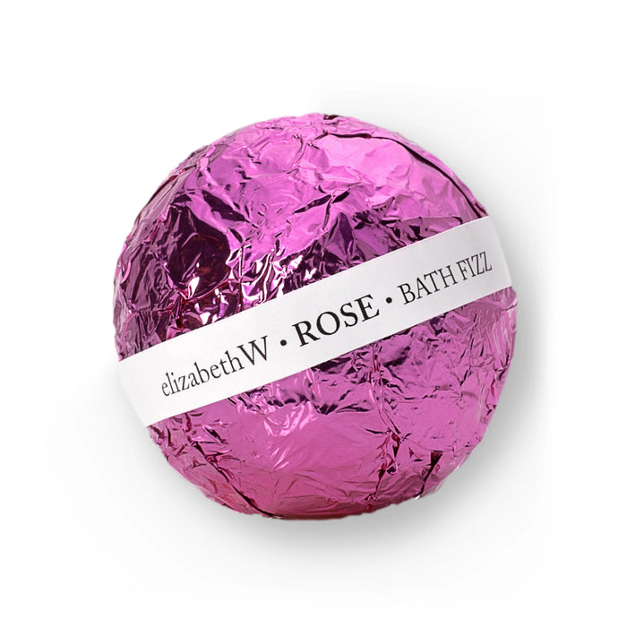 A round, fragrant BATH FIZZ BALL ROSE from E WIGHTMAN & CO is wrapped in shiny pink foil with a white label and displayed against a white background.