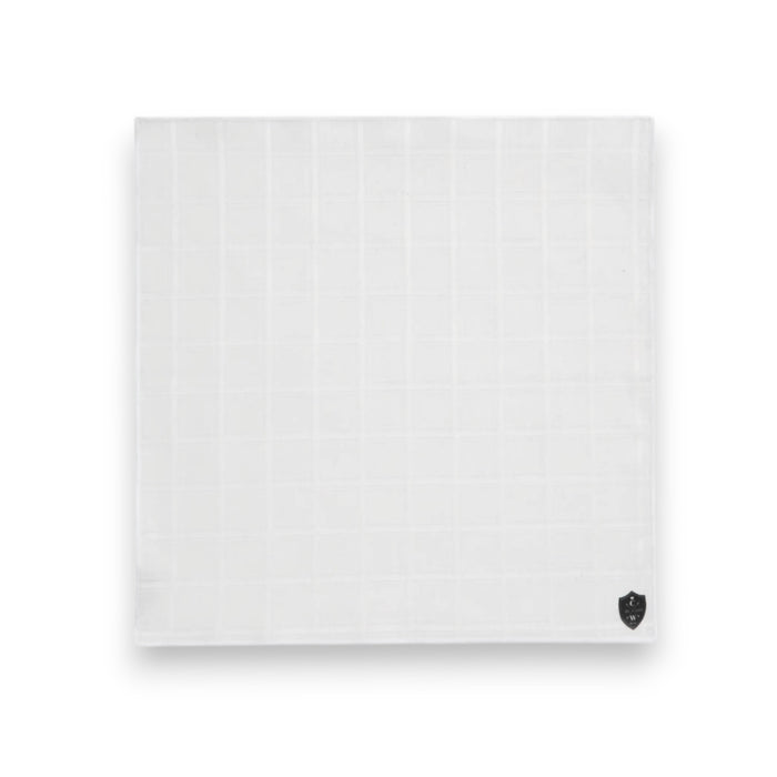 The CLIFTON WILSON - WHITE LINEN WINDOWPANE POCKET SQUARE features a subtle check pattern and a small black logo in one corner, shown neatly folded on a white background.