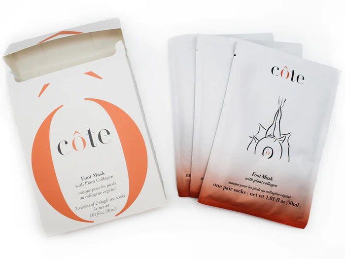 A white package with orange accents, partially open to show multiple sheet masks inside. The label reads "COTE," highlighting plant-based collagen for age-defying hydration. Product: COTE - FOOT MASK WITH COLLAGEN 3 PACK.