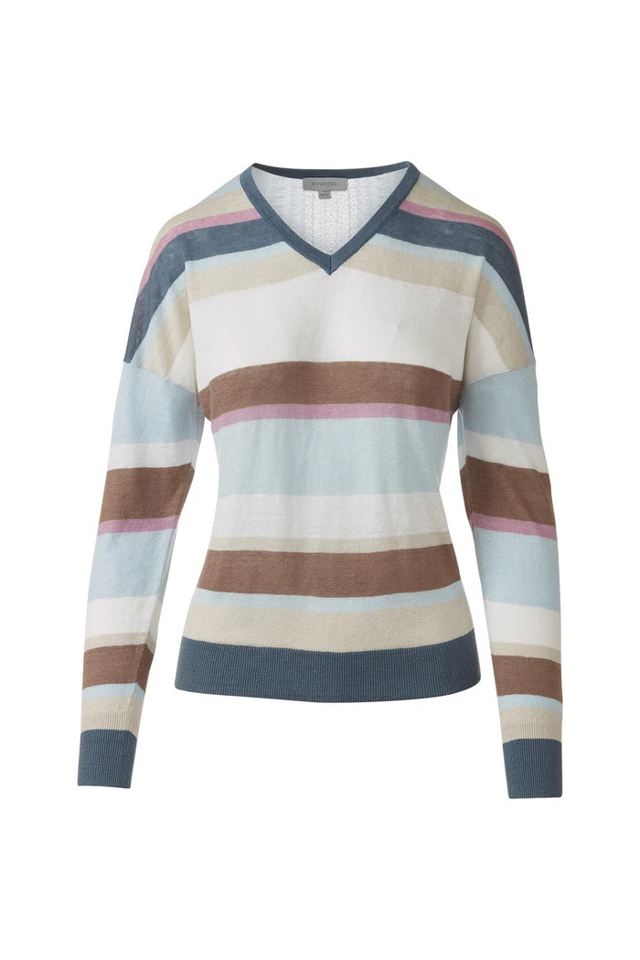 A woman with dark hair in a ponytail wears the KINROSS CASHMERE Multi Color Stripe Vee Neck Linen Sweater and blue jeans, standing with her hands in her pockets and smiling slightly against a white background.