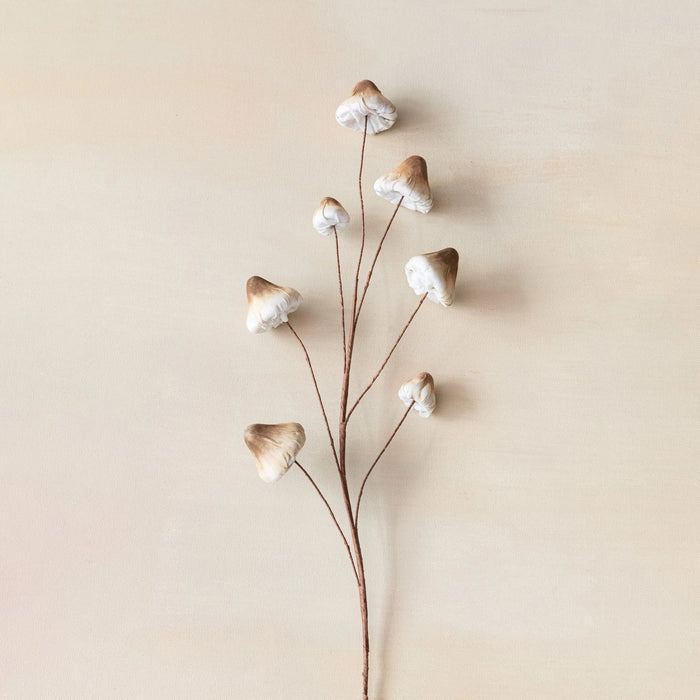 The MUSHROOM SPRAY STEM by CREATIVE COOP presents a delicate arrangement of small mushrooms with light brown caps on thin stems, set against a beige background, reminiscent of minimalist botanical art. This whimsical decor piece introduces nature's charm to your home, featuring enchanting foam and fabric mushrooms.