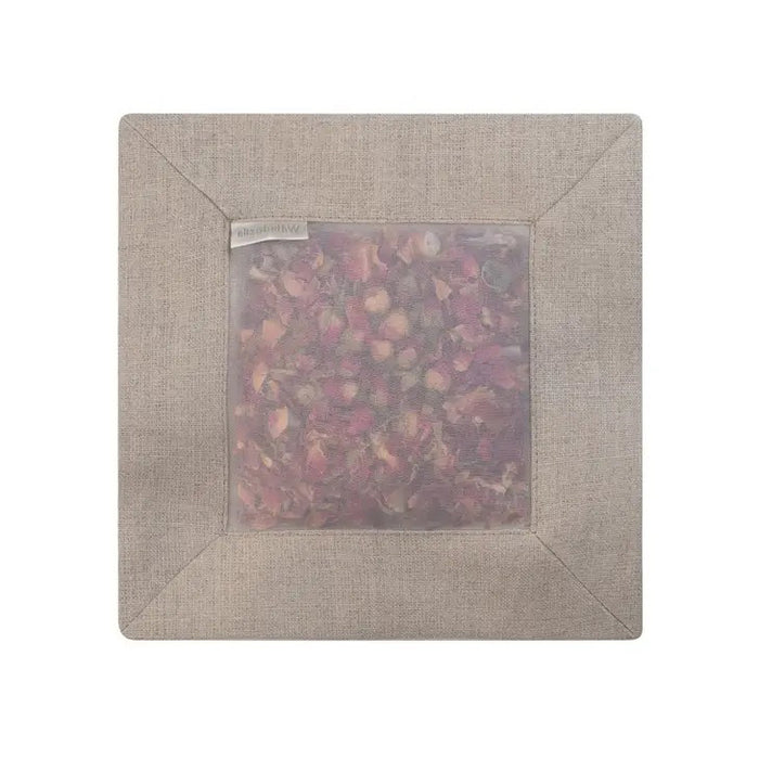 The SQUARE ROSE SACHET IN NATURAL LINEN by E WIGHTMAN & CO is a linen pouch filled with dried rose petals, gently scenting clothes while its translucent fabric shows the pink and red petals inside.