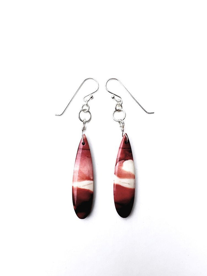 The ANN LIGHTFOOT Mookite Drop Earrings boast a long, teardrop shape with a stunning marbled design in vibrant red and white hues. Mounted on sterling silver hooks, they are beautifully showcased on a pristine white background.