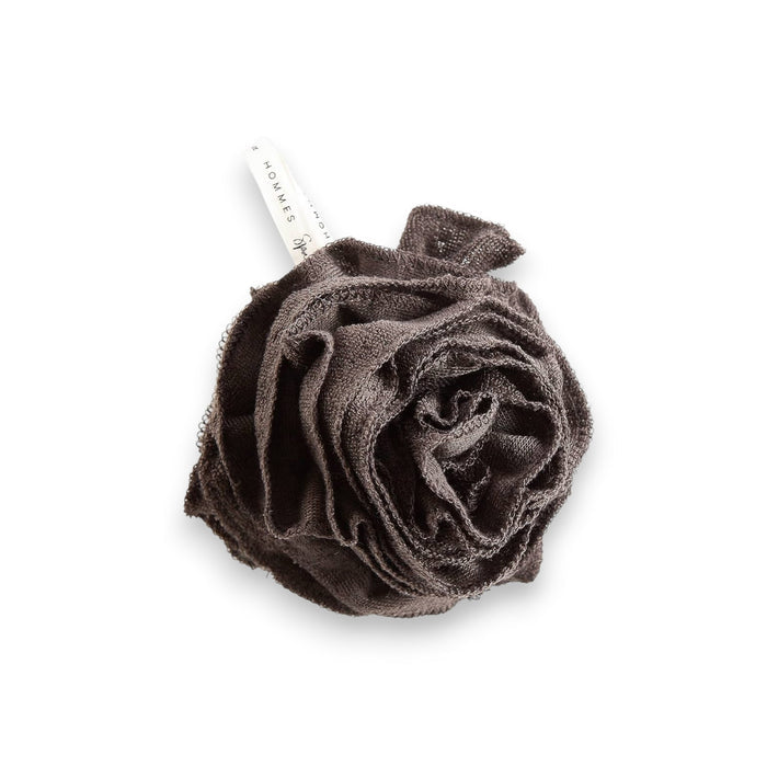 A black bamboo pouf, an eco-friendly bath accessory, nestled inside grey and gold packaging. The label reads "EUROPEAN SOAPS, LLC" with a sleek design that includes geometric patterns and the words "Hommes" and "Spa Privé".