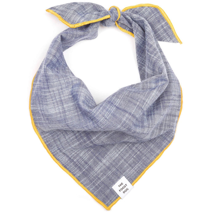 A blue and white plaid BANDANA by THE FOGGY DOG, accented with yellow trim and tied in a top knot. It features a small white tag at the bottom corner displaying the brand name.