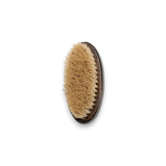 A BAUDELAIRE - BEECHWOOD 4" NAIL BRUSH with a dark wooden handle and natural boar bristles is placed next to its decorative box. The box features a design with leaves and an illustration of a tree, along with the brand name "BAUDELAIRE.