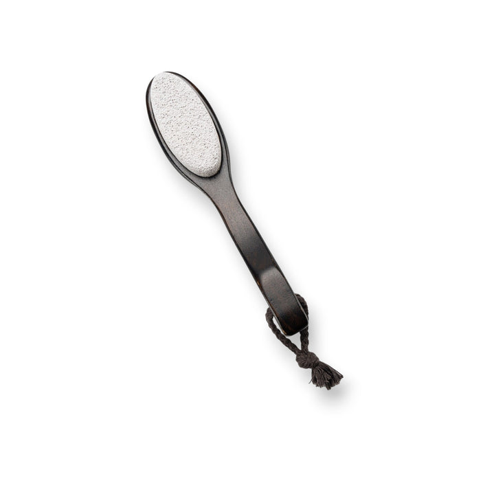 A two-sided foot file with a wooden handle and attached rope, featuring natural pumice on one side and a black abrasive surface on the other. The product, BAUDELAIRE - BEECHWOOD 8" FOOT FILE by BAUDELAIRE, is laid next to its box, which has a botanical design and the branding "Beechwood Foot File" inspired by Japanese rituals.