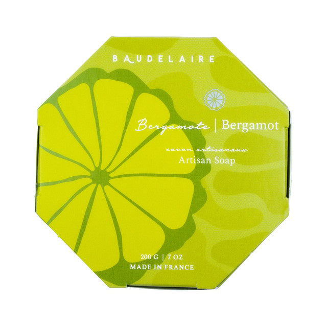 A green octagonal box labeled “BAUDELAIRE - BERGAMOT 7OZ BOXED BATH BAR,” featuring a yellow citrus slice design and containing a 200g French-milled soap enriched with shea butter, delivers a luxurious and refreshing bergamot fragrance. Made in France.