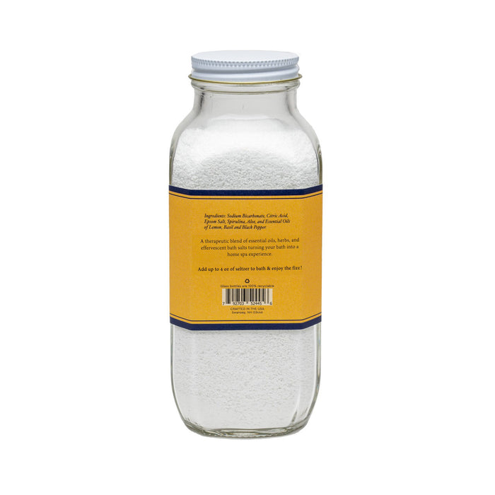 A clear glass jar of BAUDELAIRE DETOX BATH SELTZER 18oz features a yellow and blue label with "Handmade," "Therapeutic," and essential oils. Perfect for relaxing, effervescent soaks. Brand: BAUDELAIRE.