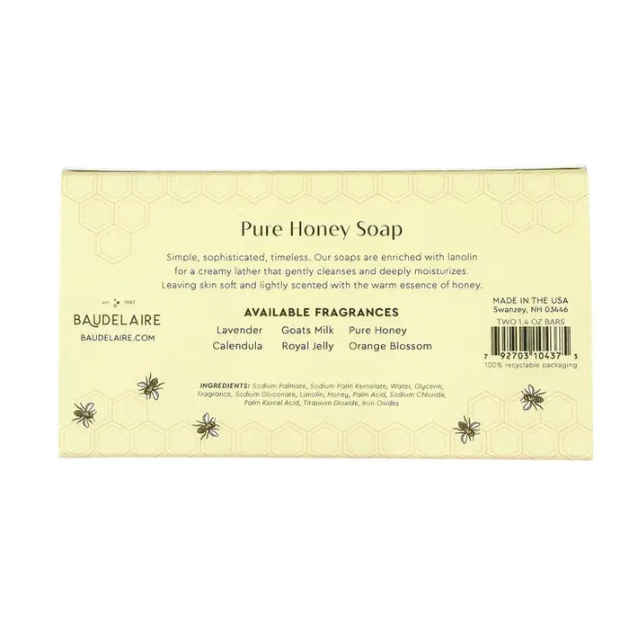 Two BAUDELAIRE soap boxes with floral designs, one opened to reveal a honeycomb patterned soap bar inside. Labels show 'Pure Honey' and 'Royal Jelly'. Text on the side reads "Crafted by Artisans. Cherished by You." The BAUDELAIRE - PURE HONEY SOAP 1.4OZ MATCHBOX DUO is the perfect gift for any occasion. Background is plain white.