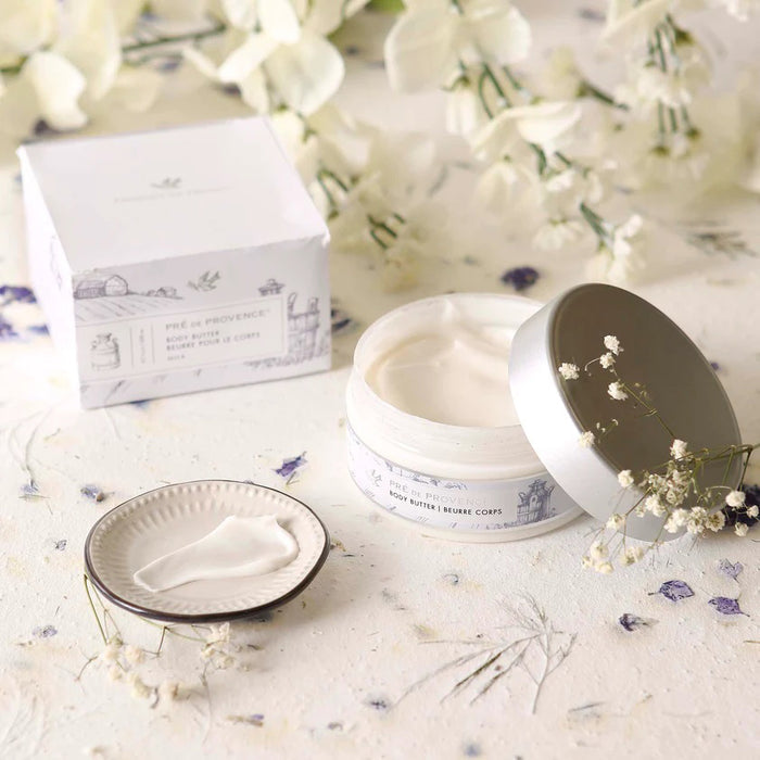 A 6.7 oz (200 ml) jar of EUROPEAN SOAPS, LLC BODY BUTTER - MILK features a silver lid and building sketch packaging. Enriched with Shea Butter for deep moisture.