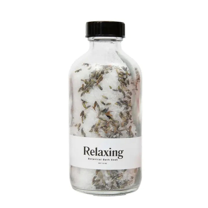 A clear glass jar with a black lid holds GIFTEN MARKET's BOTANICAL BATH SOAK - RELAXING, a white detox blend with dried lavender peppermint. The label reads "BOTANICAL BATH SOAK - RELAXING.
