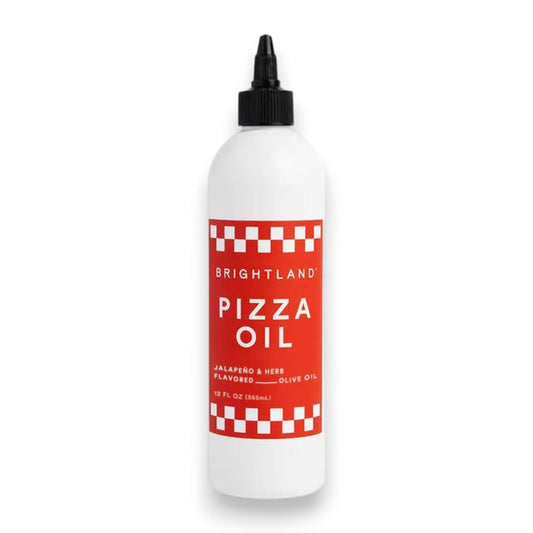 A white bottle features a red label that reads "BRIGHTLAND - PIZZA OIL." The label emphasizes the "Jalapeño & Herb Flavored Olive Oil," highlighting an herbaceous essence. The bottle has a black cap and is displayed against a plain white background.