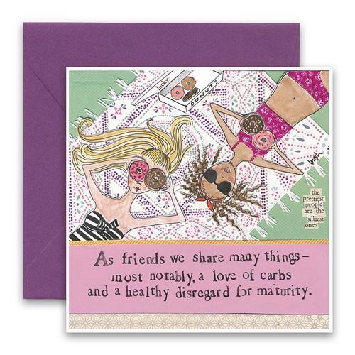 CURLY GIRL DESIGN, INC’s CURLY GIRL DESIGNS - LOVE OF CARBS GREETING CARD features two women in swimsuits on a picnic blanket, holding donuts to their faces—a playful tribute to friendship and a shared love of carbs.