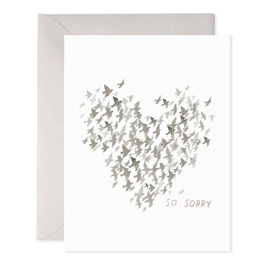 The E. FRANCES PAPER - STARLINGS CONDOLENCE GREETING CARD features a heart made of small gray birds on luxurious paper. Below, "SO SORRY" is printed in muted pink. An elegant envelope is partially visible behind the card.