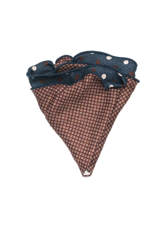 The EDWARD ARMAH - SILK REVERSIBLE POCKET CIRCLE NAVY DOTS is shown neatly folded on a white background, highlighting its blue side with white and brown polka dots and contrasting geometric pattern on the reverse.