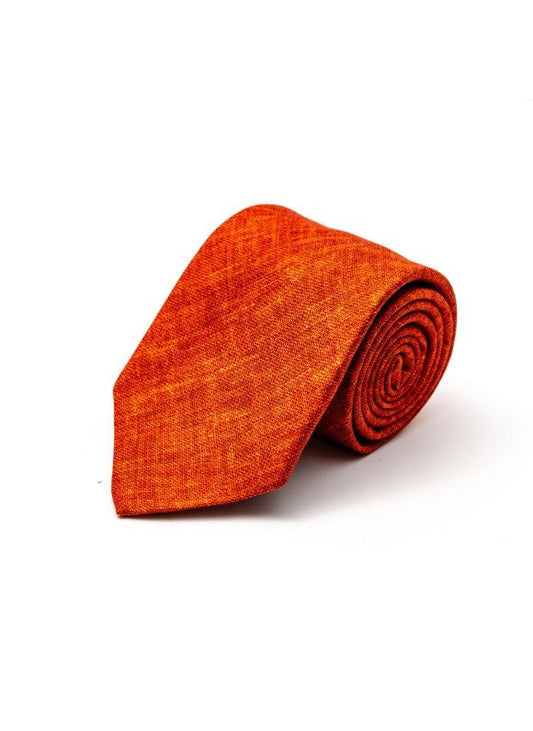The EDWARD ARMAH Solid Rust Silk Tie, featuring a subtle textured finish, is neatly rolled on a white background.