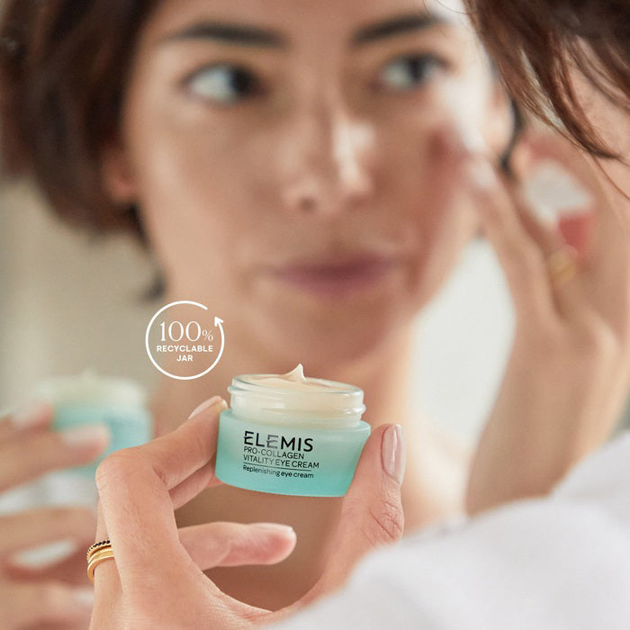A light blue jar of ELEMIS - PRO-COLLAGEN VITALITY EYE CREAM by ELEMIS - STEINER, filled with creamy off-white product. The label says "Replenishing eye cream" and the jar sits on a white background with a visible reflection beneath it.