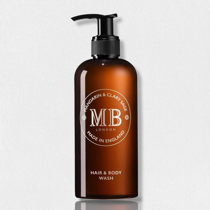 A brown pump bottle labeled "Molton Brown 1971 Collection Mandarin Clary Sage Hair & Body Wash" is displayed against a light background, featuring a refreshing mandarin and clary sage blend for both hair and body.