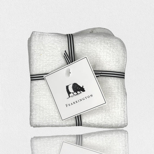 A set of four white waffle face cloths from the FEARRINGTON LIFESTYLE TOWEL COLLECTION by HARBOR LINEN, tied with a black-and-white striped ribbon and a cow-illustrated "FEARRINGTON" tag. Ideal for gentle makeup removal.