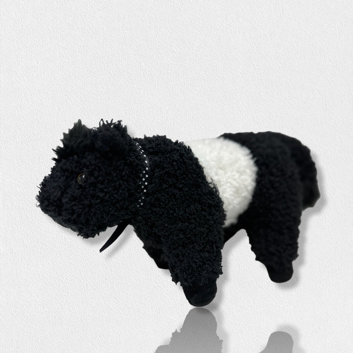 The FEARRINGTON SIGNATURE COLLECTION - BELTIE COW PLUSH TOY by BEVERLY HILLS TEDDY BEAR CO features a fluffy black and white cow design, with a white midsection and black head, legs, and tail, standing on a light surface against a plain background.