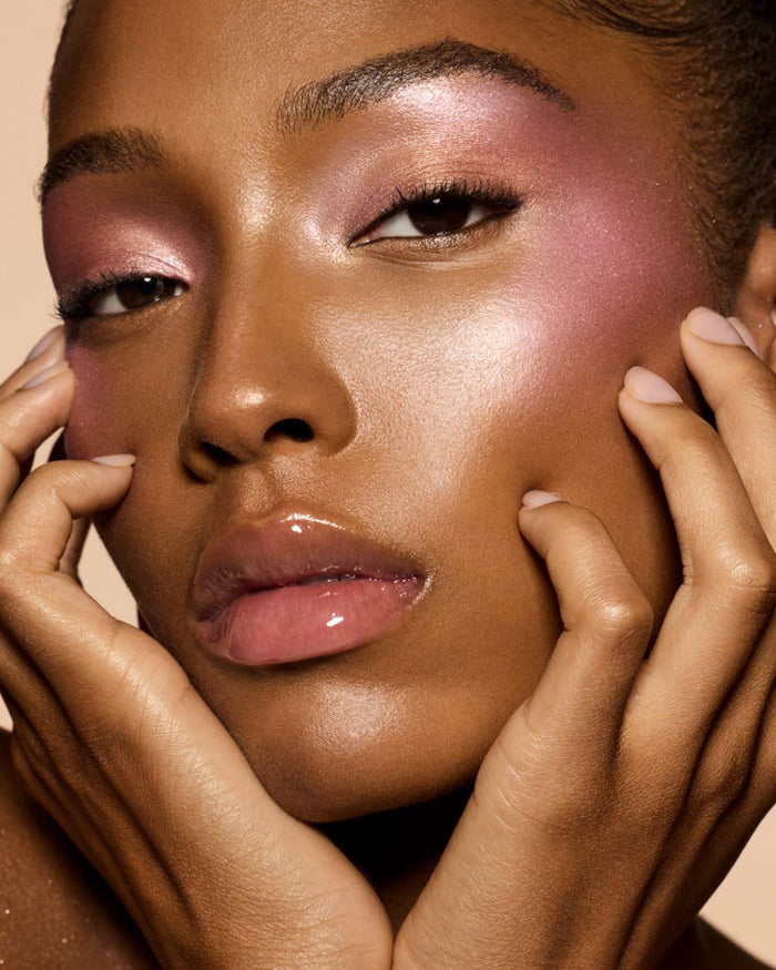 deep skin tone model wearing Gloss Bomb Heat Universal Lip Luminizer Plus Plumper in shade glass slipper heat