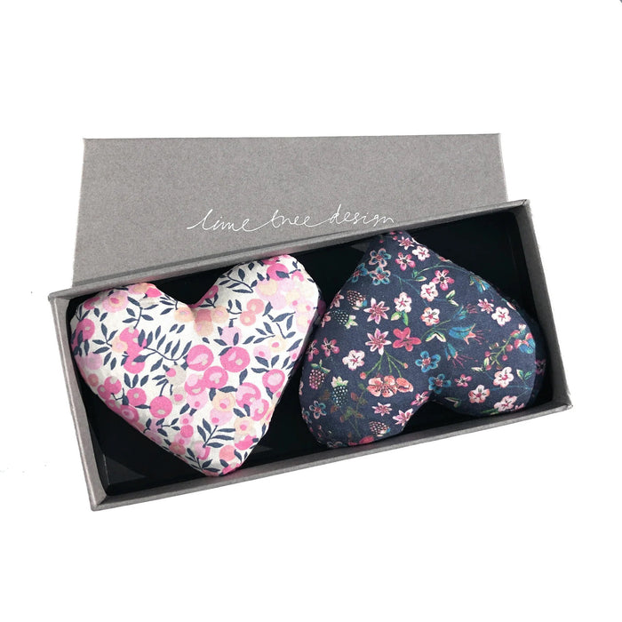 Two fabric heart-shaped LIME TREE COLLECTION LTD "HEARTS - LOVEY DOVEY SACHET" in pink floral and dark blue Liberty Tana Lawn are presented in a grey "lime tree design" box. Ideal as lavender drawer sachets.