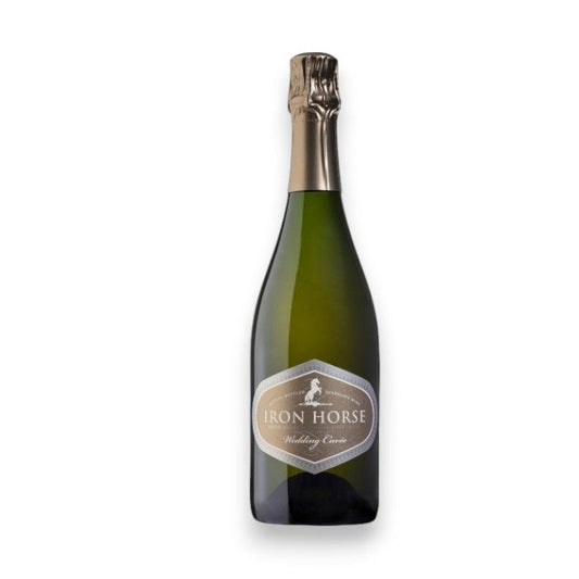 An Iron Horse Wedding Cuvée, by Johnson Bros./Mutual/Epiphany, showcases a dark green glass bottle with foil on its neck. The label states "IRON HORSE WEDDING CUVEE," set against a plain white background, reflecting the elegance of Sonoma County's Russian River Valley.