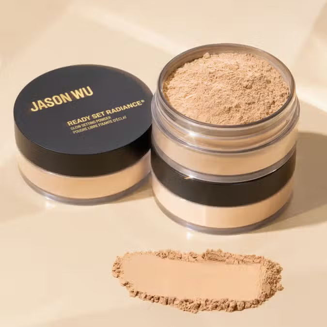 Two JASON WU BEAUTY READY SET RADIANCE POWDER containers are shown—one open to reveal the loose, hydrating powder, the other closed. A front swatch displays the luminous finish of this JASON WU BEAUTY product.