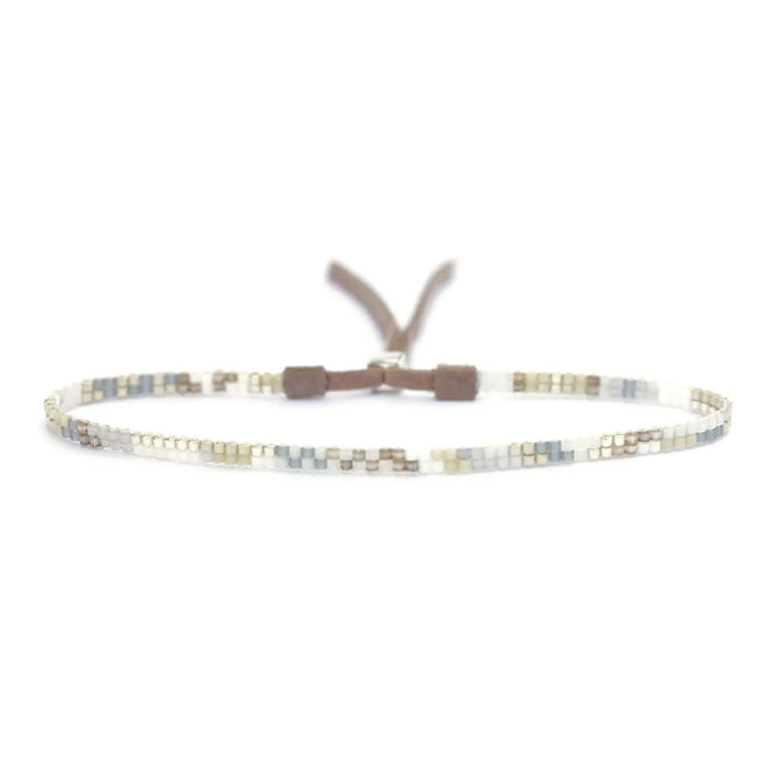The JULIE ROFMAN - MINI BRACELET by JULIE ROFMAN JEWELRY is a vibrant handwoven piece adorned with small, square beads in various shades of pink, red, and white. It is displayed against a white background and includes a straightforward sterling silver clasp for convenient fastening.