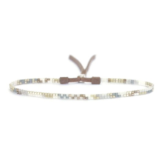 The JULIE ROFMAN - MINI BRACELET by JULIE ROFMAN JEWELRY is a vibrant handwoven piece adorned with small, square beads in various shades of pink, red, and white. It is displayed against a white background and includes a straightforward sterling silver clasp for convenient fastening.