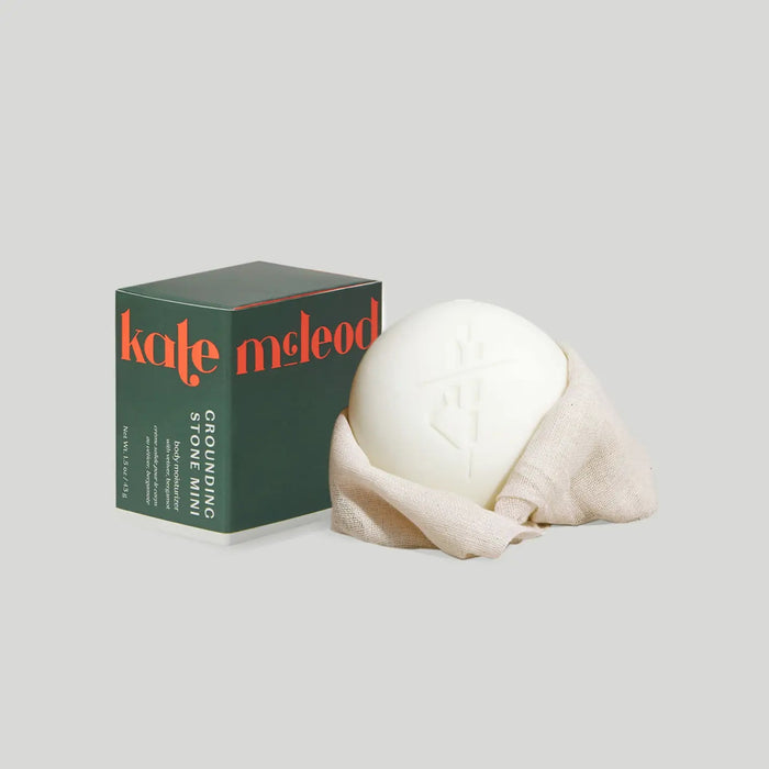 The KATE MCLEOD GROUNDING STONE MINI LOTION BAR 1OZ blends grounding vetiver root and uplifting bergamot lemon to soothe tension and nourish skin, offering a plastic-free skincare solution.
