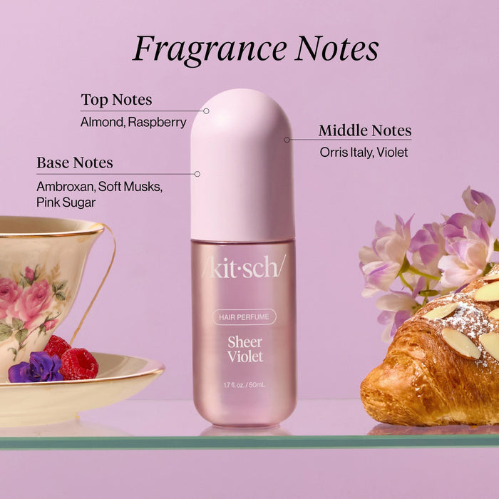 A 1.7 fl oz bottle of KITSCH - HAIR PERFUME MIST IN SHEER VIOLET sits beside its coordinating lavender box against a light gray background. Both the bottle and box feature the product and brand name in white text, emphasizing this sophisticated hair perfume mist from KITSCH, characterized by floral-fruity-musk notes and advanced odor-eliminating technology.