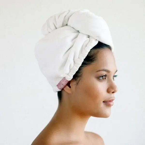 The KITSCH - QUICK DRY HAIR TOWEL, suitable for frizzy, curly, or straight hair, comes in a clear plastic bag labeled "/kit·sch/ CLEANSE," and boasts quick-drying microfiber that effectively reduces frizz.
