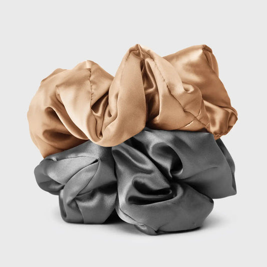 A KITSCH - SATIN SLEEP PILLOW SCRUNCHIES box includes two large satin scrunchies—one gold, one gray—shown outside the box to showcase their soft, frizz-reducing texture.
