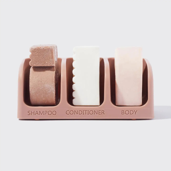 The KITSCH Self Draining Soap Dish for 3 Bars features labeled compartments for shampoo, conditioner, and body bars. Its eco-friendly, self-draining design keeps bars dry, all displayed against a plain light background.