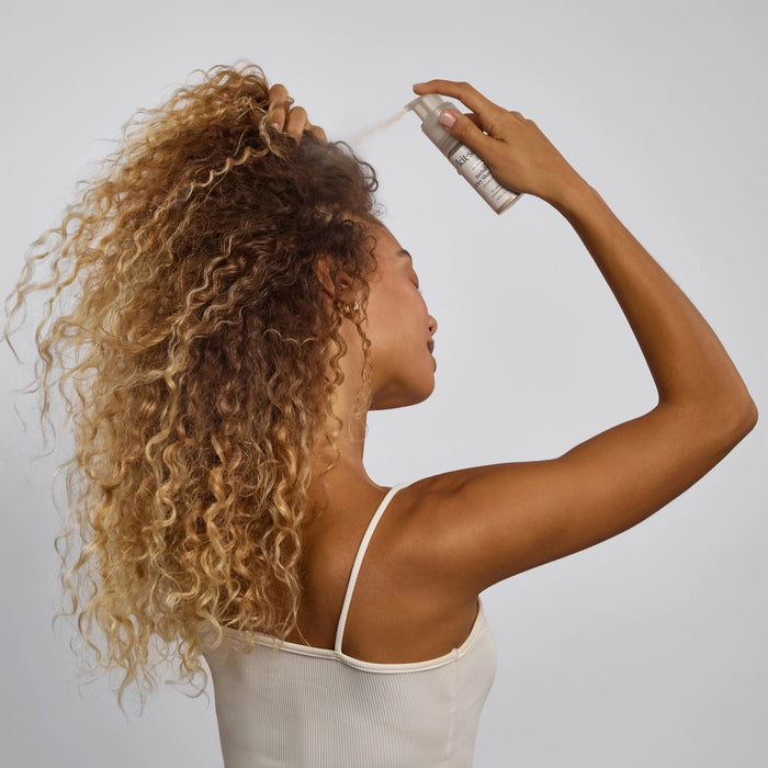 A bottle of KITSCH Volumizing Invisible Rice Protein Dry Shampoo stands upright on a light background. This non-aerosol, mess-free formula by KITSCH refreshes your hair with rice protein and comes with a clear cap and white label.