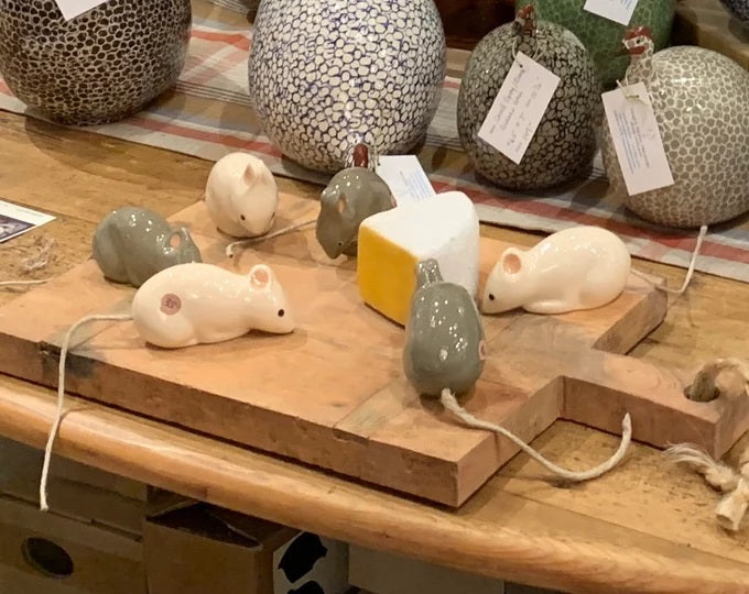 The LES CERAMIQUES DE LUSSAN - GREY SITTING MOUSE features a delicate gray ceramic body, long slender tail, and charming pink details inside its ears, all set against a white background. Handmade by LES CERAMIQUES DE LUSSAN, this delightful figurine pairs perfectly with any of the brand's ceramic cats and showcases the exquisite artistry of handcrafted ceramics.