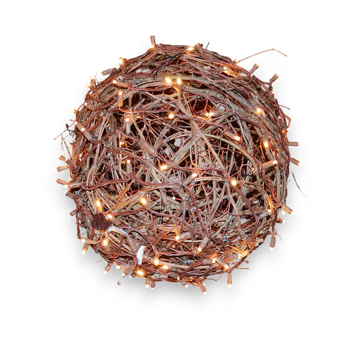 The PRE-LIT GRAPEVINE BALLS by EGRAPEVINESTORE is a 14-inch round, decorative nest made of intertwined twigs, adorned with tiny grapevine balls and mini Christmas lights for a warm glow against a plain white background.