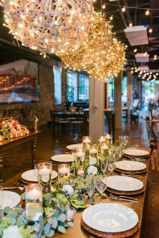 The PRE-LIT GRAPEVINE BALLS by EGRAPEVINESTORE is a 14-inch round, decorative nest made of intertwined twigs, adorned with tiny grapevine balls and mini Christmas lights for a warm glow against a plain white background.