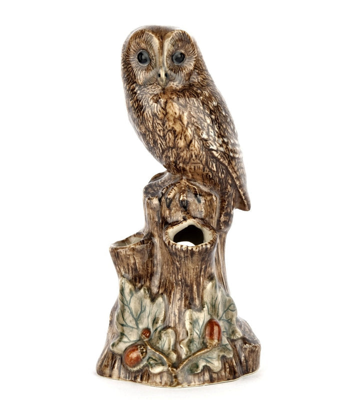 The QUAIL CERAMICS Tawny Owl Bud Vase by QUAIL DESIGNS features a hand-painted stoneware owl perched on a textured tree stump with green leaves and brown acorns at the base, set against a white background.