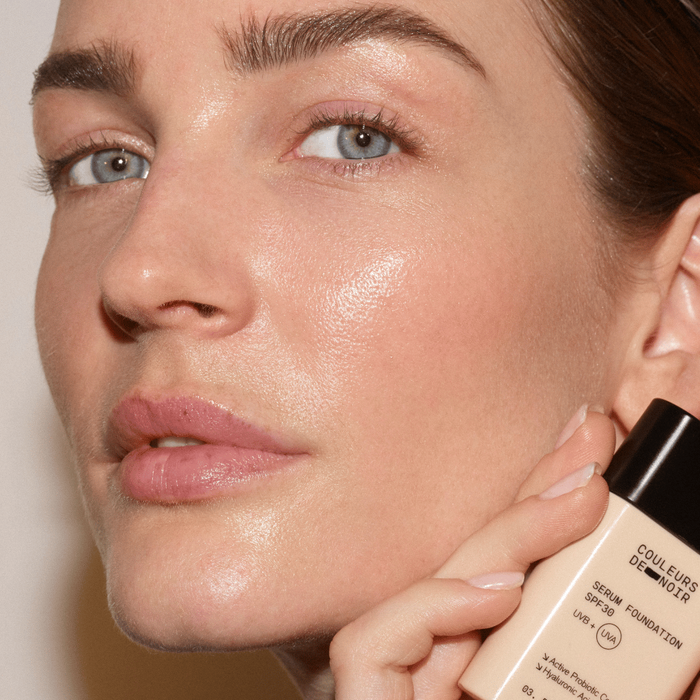Close-up of a person holding a foundation bottle with a blurred background