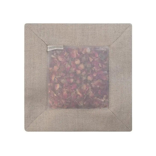The SQUARE ROSE SACHET IN NATURAL LINEN by E WIGHTMAN & CO is a linen pouch filled with dried rose petals, gently scenting clothes while its translucent fabric shows the pink and red petals inside.