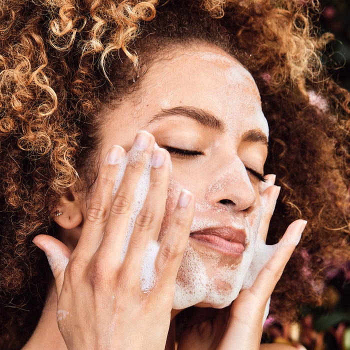 Woman washing her face with lots of soap suds.