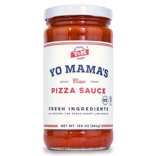A clear glass jar of YO MAMA'S FOODS PIZZA SAUCE with a white lid showcases the No Added Sugar, keto-certified red sauce. The side label lists ingredients, nutrition facts, social media icons, and a bar code.